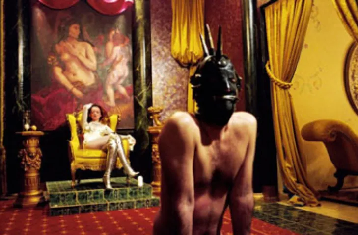 Inspirez-vous de cette scène pour créer un coin pouvoir dans votre donjon BDSM maison. L'élément central est souvent un meuble BDSM symbolique comme ce fauteuil-trône, qui définit l'atmosphère de votre pièce BDSM ou salle de bondage. Que vous aménagiez une maison BDSM entière ou un simple coin, ce type de mobilier renforce les dynamiques de jeu. C'est une excellente idée BDSM pour un donjon BDSM pervers sans nécessiter de grands travaux, prouvant que le BDSM à la maison peut être à la fois simple et impactant.
