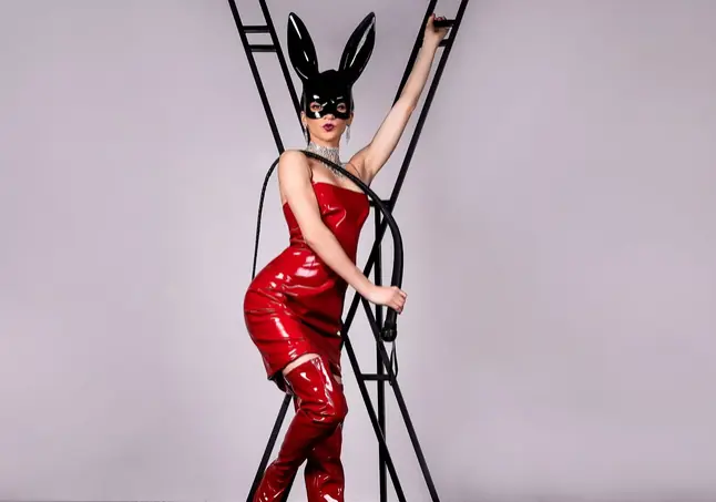 Femme en latex rouge avec oreilles de lapin sur une croix BDSM