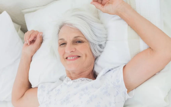 Femme mature souriante allongée dans un lit