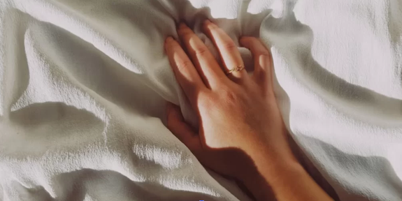 Main posée sur des draps blancs